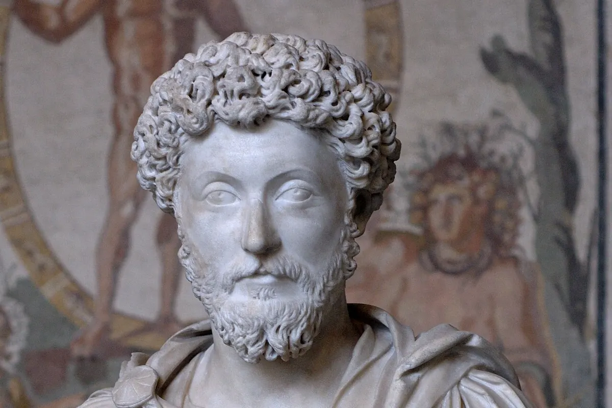 Foto patung dada marmer Marcus Aurelius berambut ikal dan berjanggut, mengenakan jubah, dengan latar mosaik Romawi berwarna di dinding Glyptothek München